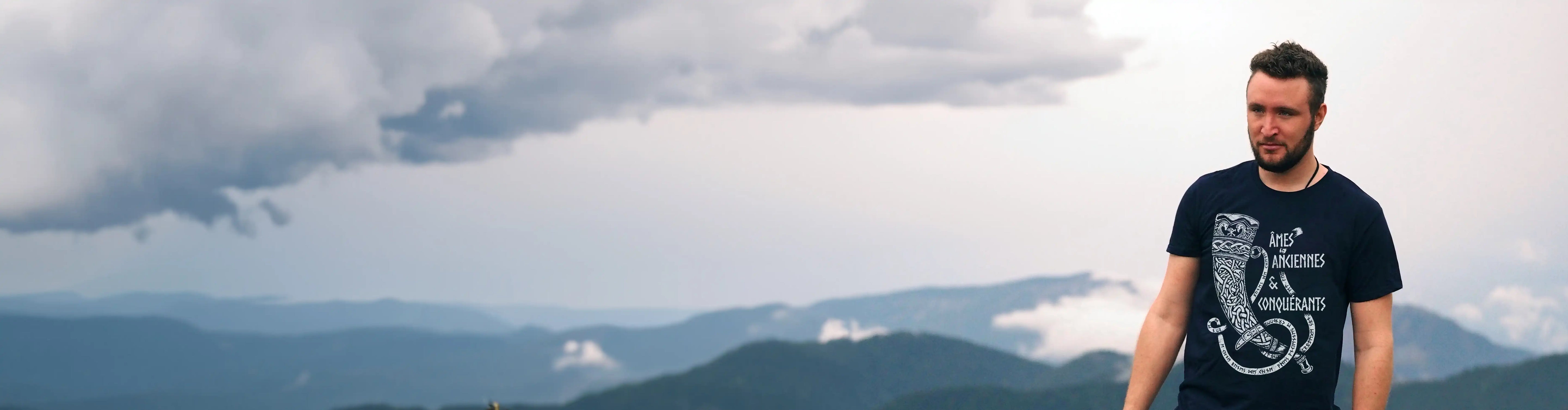 Thibaut Comte on top of a mountain wearing a t-shirt Runes de Chêne