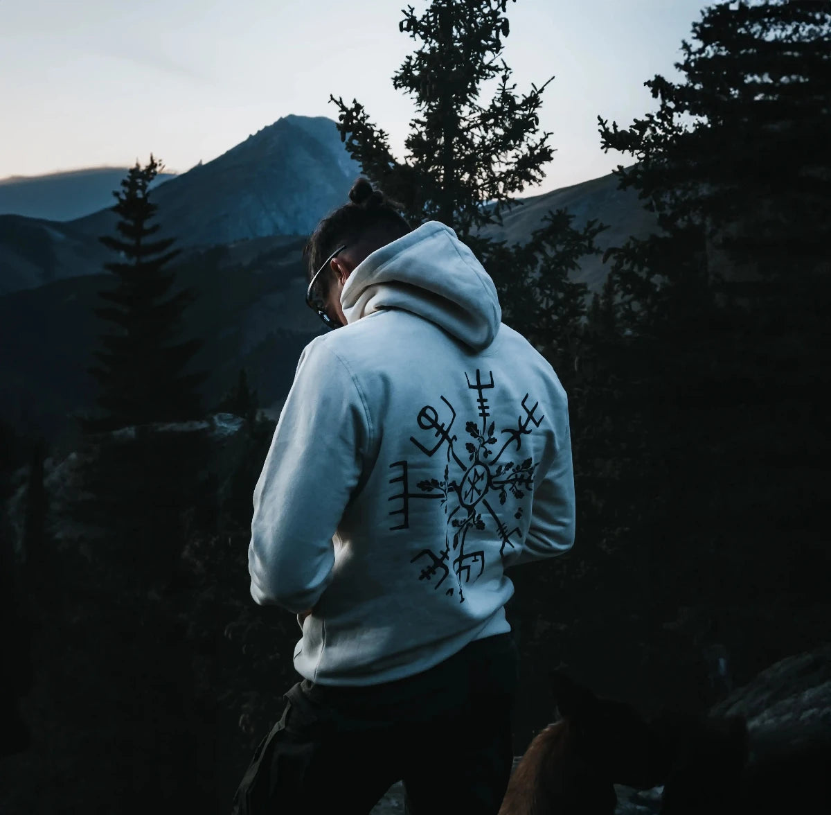 Un jeune homme dans une forêt vu de dos portant un sweat-shirt de couleur blanc 
vegvisir ou la boussole nordique de la marque Runes De Chêne